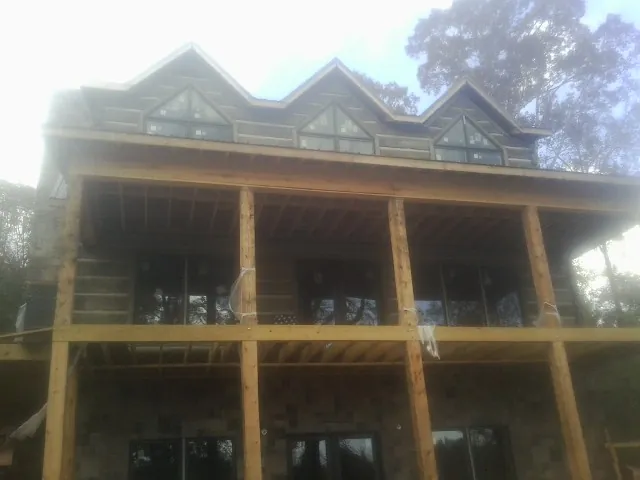 Dormers and porch framing on a large log home under construction — Roof Coating work by our crew in Lee