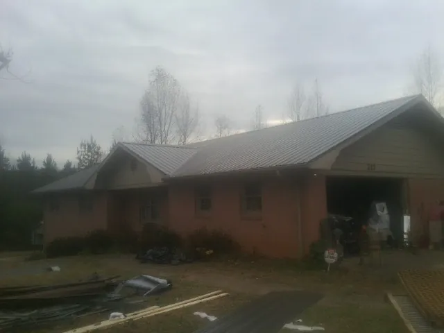 Gray metal roof on a stucco house with an attached garage in Lee