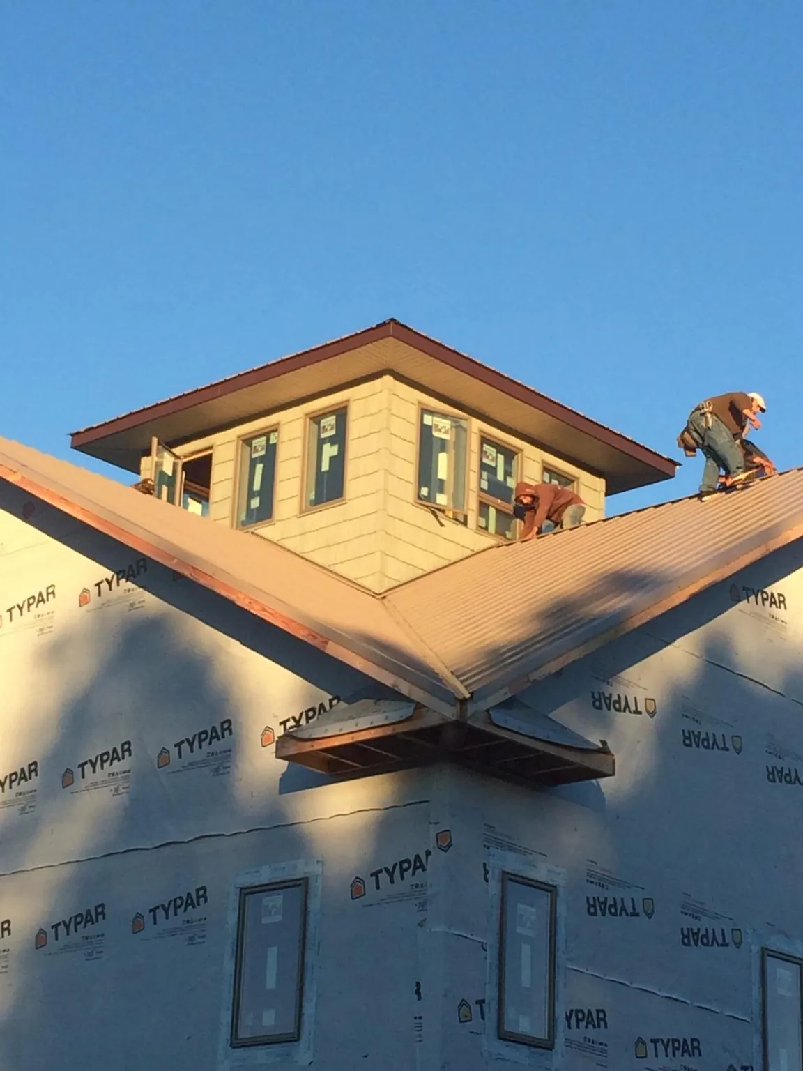 Roofers working around a rooftop cupola on a new metal roof at sunset — Roof Waterproofing in Lee by Roofing Brothers